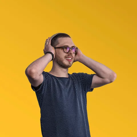 Filip Bednárik laughing, hands on head, on a yellow background